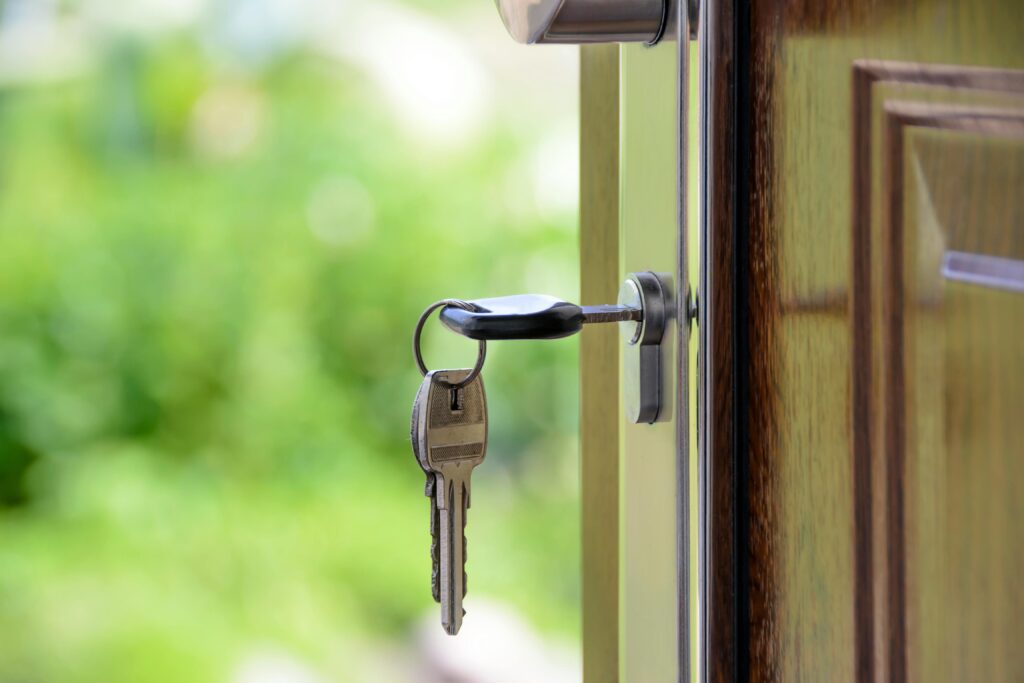 An old-style key hanging on a wooden door, representing home security systems.
