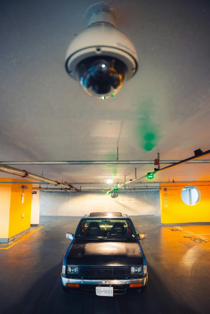 A vintage Nissan pick-up truck parked in an underground garage under surveillance.